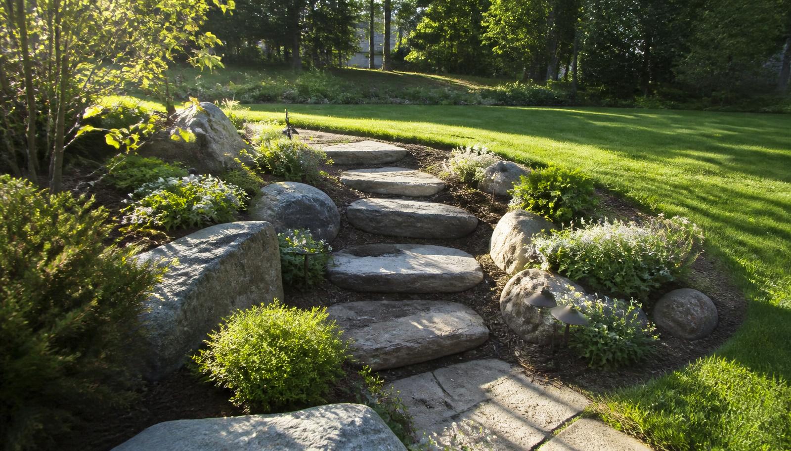 Backyard landscape with natural stone steps, terraced planting beds and manicured lawn